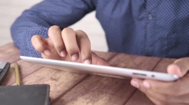 Adam el ile ofis masasında dijital tablet üzerinde çalışıyor, kendi yarattığı grafiği kullanarak. 