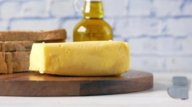 Kesme tahtasında tereyağı kesme ve arka planda kahverengi ekmek 