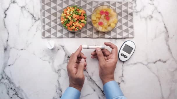 Fiatal férfi mérő cukorbeteg friss gyümölcs és zöldség az asztalon — Stock videók