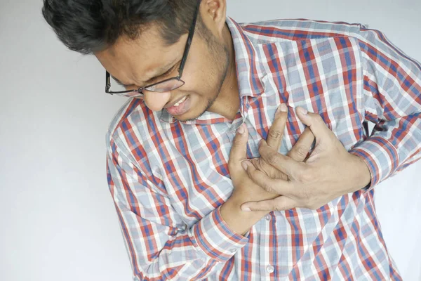 Jonge man lijden pijn in het hart en houden borst met de hand — Stockfoto