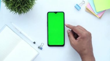Ofis masasında akıllı telefon kullanan bir adamın üst görüntüsü. 