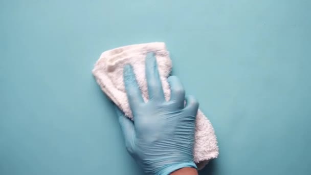 Main en gants de caoutchouc bleu table de nettoyage avec chiffon sur fond bleu — Video