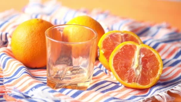 Pouring orange juice in glass on a color background — Stock Video