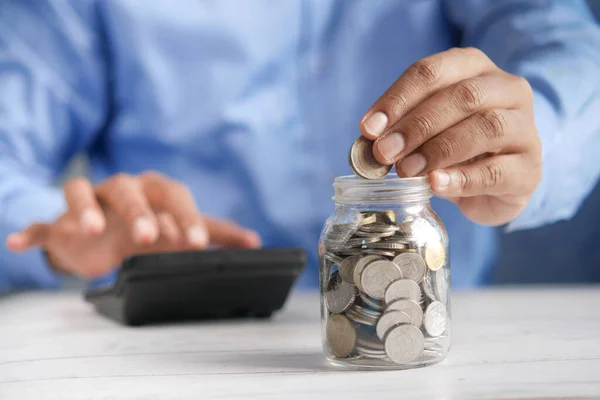 Young man saving coins in a jar white sited — Stock Photo, Image