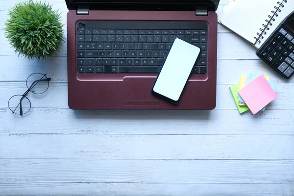 Téléphone intelligent avec écran vide, ordinateur portable sur fond en bois — Photo