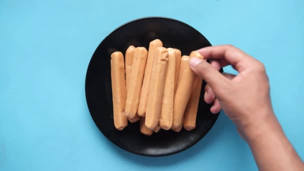 Picar las salchichas a mano en un plato sobre fondo azul — Vídeos de Stock