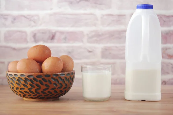 Oeufs dans un arc et un verre de lait sur la table — Photo