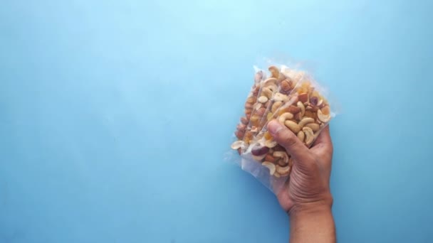 Genggam tangan paket kacang campur pada latar belakang biru — Stok Video