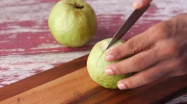  Guava 'yı doğrama tahtasıyla kesen genç adam. ,