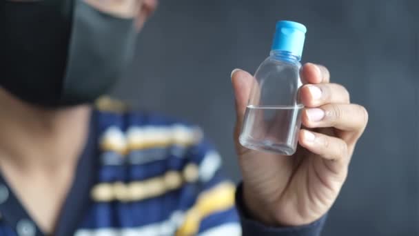 Joven hombre con mascarilla de mano agarre desinfectante — Vídeos de Stock