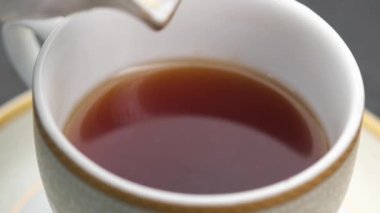 Sütü çayla bardağa dolduruyorum. ,