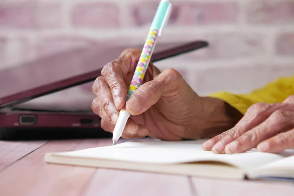 Close up de mulheres seniores mão escrita no bloco de notas. — Fotografia de Stock