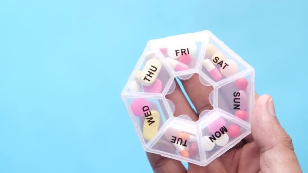Man hand hålla en medicinsk piller låda på blå — Stockvideo