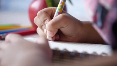 Yüzü maskeli çocuk defteri çiziyor..