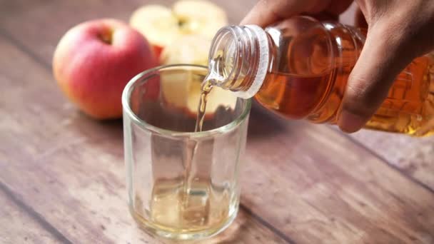 Наливая яблочный сок в стакан на стол — стоковое видео