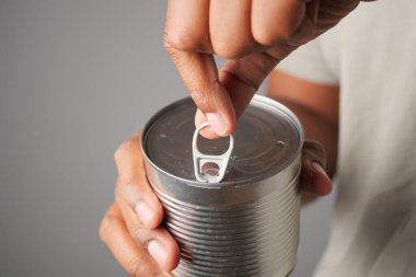 Bir insan mutfaktaki metal bir teneke kutunun çekme aletini kaldırıyor..