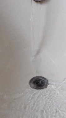 Su küvetten aşağı akıyor, küçük dalgalanmalar yaratıyor..