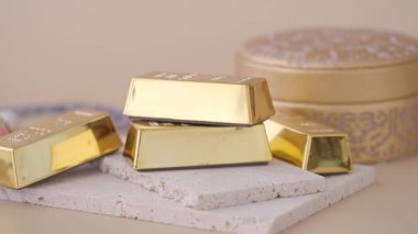 Parlak altın külçeler, yuvarlak bir kutunun yanındaki hafif bir yüzeye yerleştirilir..