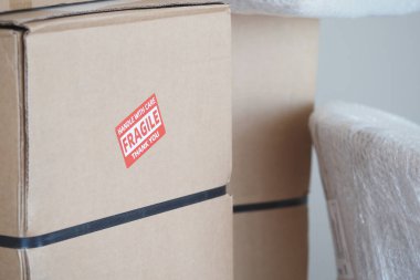 Birkaç karton kutu istiflenmiş, güvenli taşıma için kırılgan etiketler gösteriliyor..