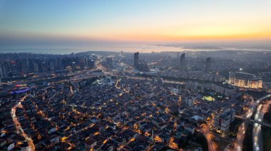 Yüksek binaların arkasında güneş batarken, İstanbul kenti ufuk çizgisi parlıyor.