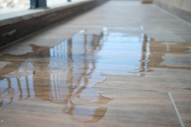 Şehir ortamında, parlak fayanslı bir yüzeyde su birikir..