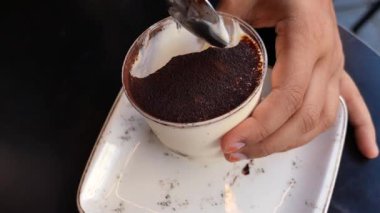 Bir el kremalı bir tatlıyı kafe çikolata sosuyla kepçeler..