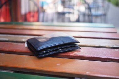 Açık havada renkli ahşap masada duran siyah cüzdan, kayıp cüzdan konsepti..