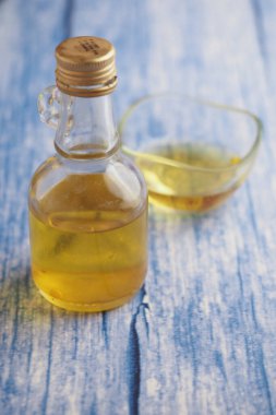 A clear glass bottle filled with oil sits beside a small dish.