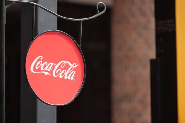 Tanıdık bir logosu olan parlak kırmızı dairesel bir tabela bir kafenin önünde asılı..