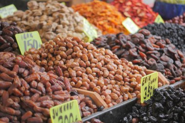 Vendors showcase a variety of dried fruits in bright colors at a market.