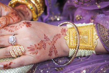 Kutlamada yüzüklerle süslenmiş ve altın bilezik takılmış bir el..