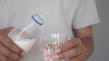 Elleri sütü bardağa doldurur, güne keyifli bir başlangıç için hazırdır.