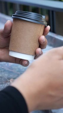 Bir insan dışarıda, elinde sıcak bir fincan kahveyle rahatlar..