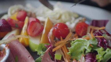 Renkli bir salata ve meyve tabağı taze malzemelerle yeniliyor..