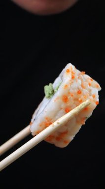 Yemek çubuklarıyla tutulmuş lezzetli suşinin tadını çıkarıyorum..