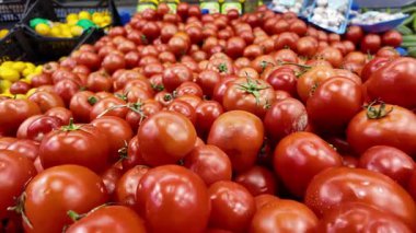 Kalabalık bir markette renkli olgun domates gösterimi.