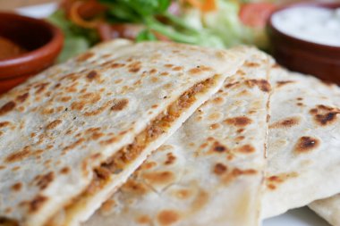 Diners savor crispy stuffed flatbreads served with fresh salad and sauces.
