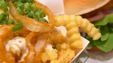 Kıvırcık patates ve hamburger taze malzemeyle servis edilir, öğle yemeği için mükemmel..