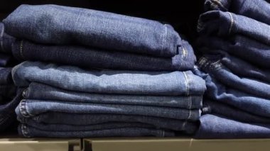 Bir mağazada düzgünce istiflenmiş kot pantolon koleksiyonunu keşfet.