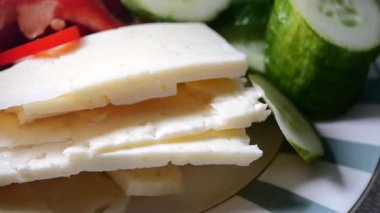 Taze peynir dilimlenmiş salatalık ve dolmalık biberle servis edilir..