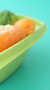 Yeşil bir kasede canlı sebzelerin mavi bir arkaplan karşısında yakın plan görüntüsü..