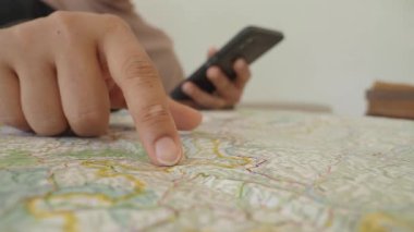 Bir kişi telefonunu kontrol ederken haritayı yakından inceler..