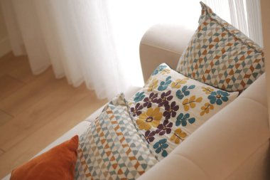 A cozy sofa with vibrant pillows adds warmth to a bright room.