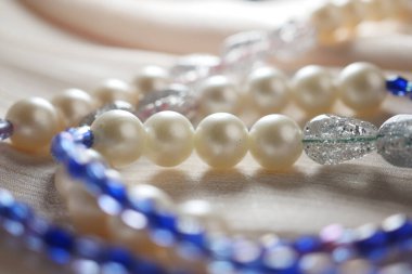 Close view of shiny beads in various colors resting on a delicate fabric.