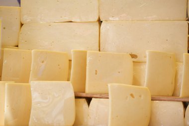 Sliced and whole blocks of mild cheese are neatly arranged for sale.
