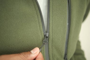 Eller rahat bir ortamda yeşil yün ceketin fermuarını çeker..