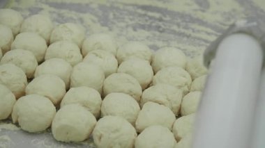 Hamur topları sıcak bir mutfakta özenle yapılır. Yumuşak ısırıklar yaratmak için adımlar.