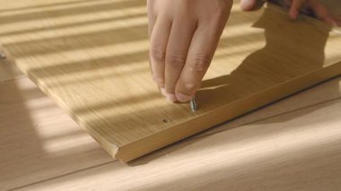 Bir insan gün ışığında ahşap bir mobilyayı dikkatlice vidalayabilir..