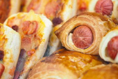Delicious pastries and hot dog rolls displayed at a bakery during breakfast.