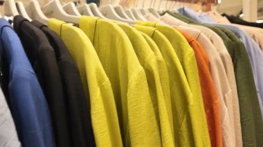 Değişik renklerde parlak gömlekler askılarda düzgün sıralanır..
